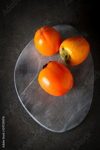 fresh persimmon on a gray stone background photo