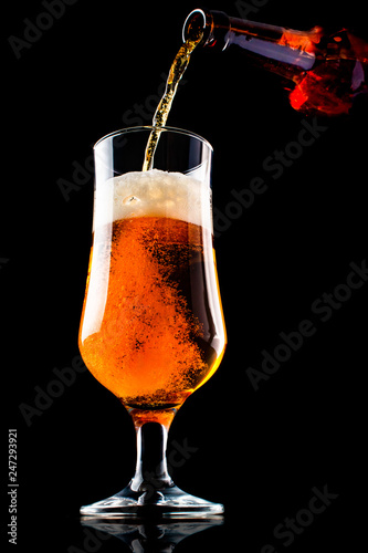 Wallpaper Mural Beer is pouring into a glass from bottle on black background Torontodigital.ca