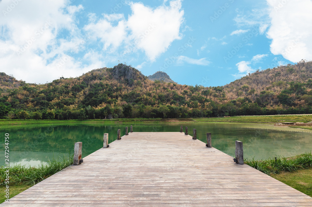 Wooden bridge or jetty with mountain and blue sky on lake
