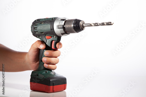  A man holds a cordless drill in his hand on a white background.