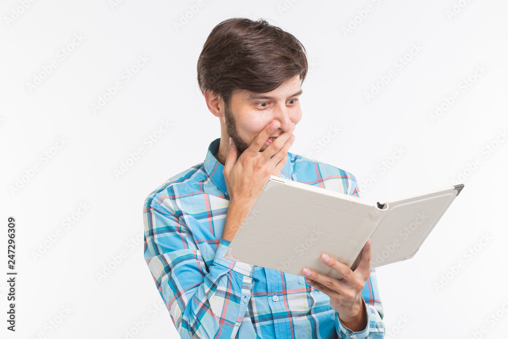 Education, leisure and people concept - young beard man reading a book and surprised Education, leisure and people concept - young beard man reading a book and surprised