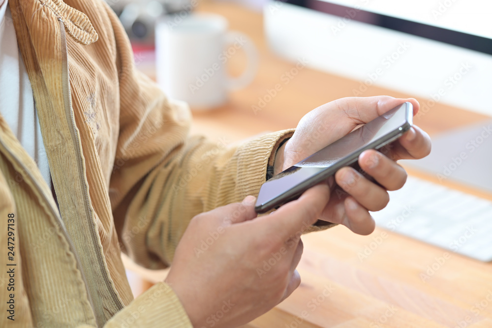 Cropped shot  of a man holding mockup mobile smart phone device on office workspace