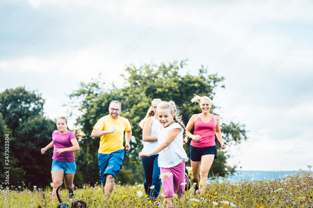 Family running on a meadow with flowers for sport Family running on a meadow with flowers for sport