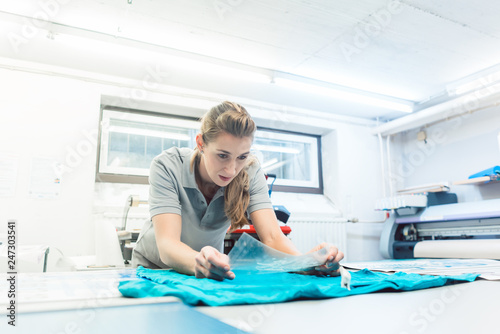 Foto Woman flock printing a T-shirt as promotional item in workshop