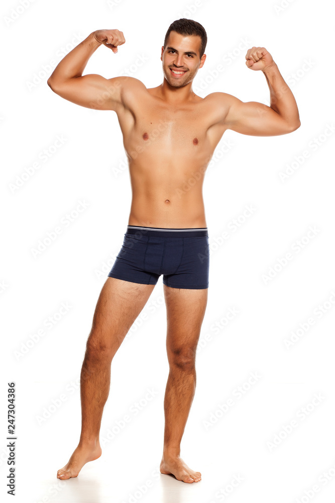 Shirtless handsome smiling man in panties on white background showing his biceps Shirtless handsome smiling man in panties on white background showing his biceps