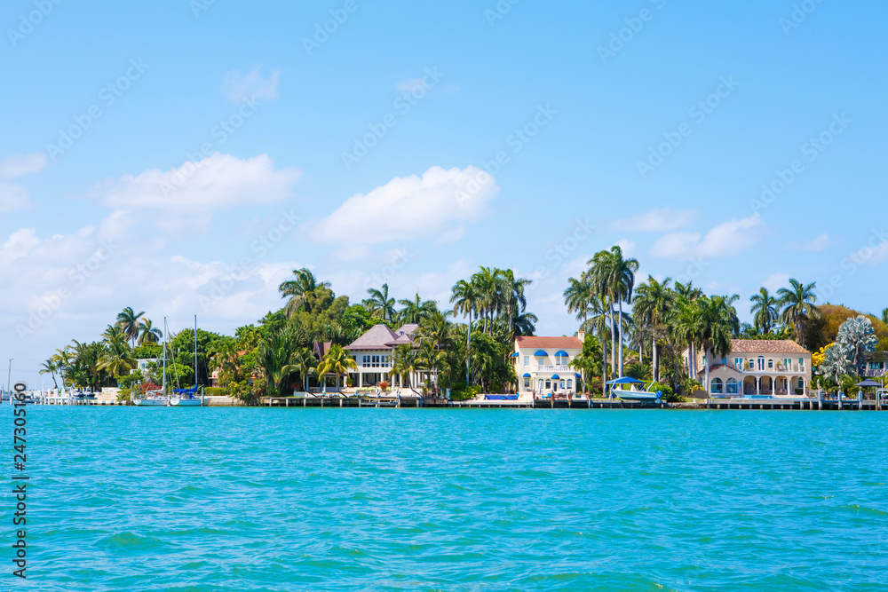 Luxury villa houses on caribbean island with ocean beach and blue sky on sunny day. With palms