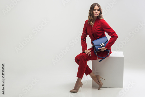 elegant woman in red suit holding blue hand bag