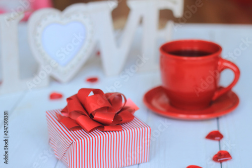 Cup of coffee and gift on blurred background.