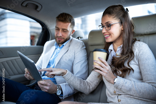 Businesswoman drinking a coffee as her partner looks in his tablet