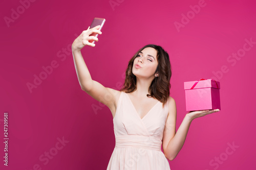brunette in a dress makes selfie and holds a gift box  © Desmi