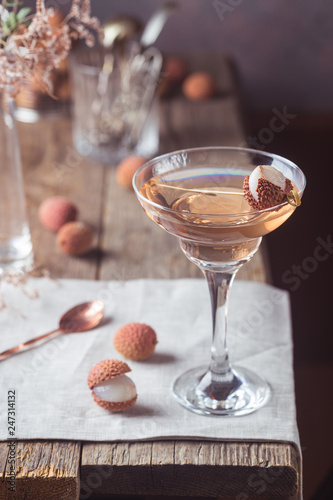 Glass of cold lychee cocktail on the old wooden table, rustic style