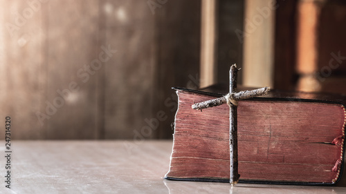 wooden cross with bible on wooden table with window light, christian concept.