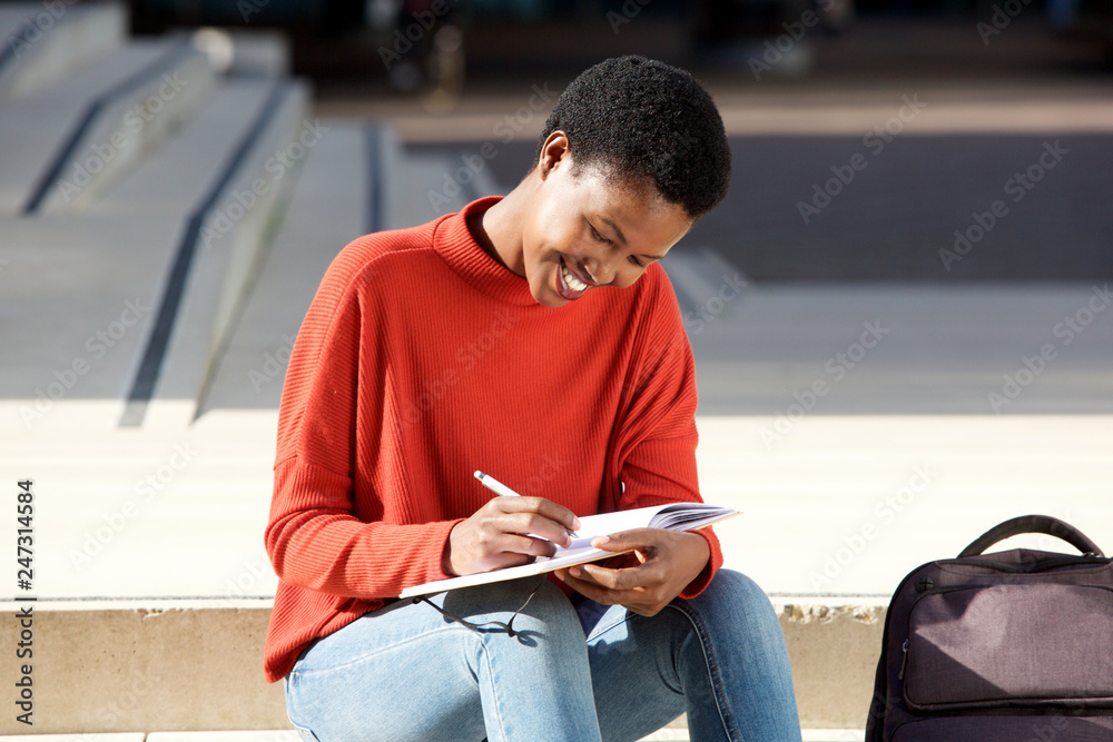 young black woman sitting outside writing in book
