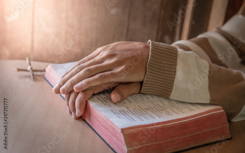 Close up hands of young man praying on bible. christian concept.
