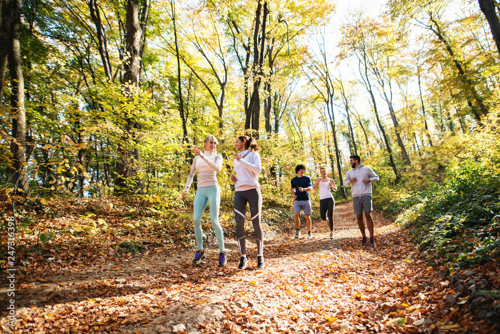 Small group of happy friends running in the woods in the autumn. Small group of happy friends running in the woods in the autumn.