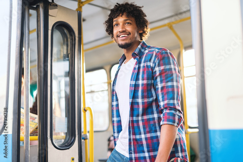 Fotografie Young smiling African American guy getting off the bus.
