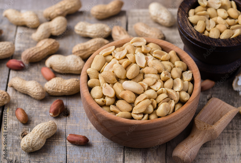 Peanuts in small wooden bowl on natural rustic desk. Peanuts in small wooden bowl on natural rustic desk.