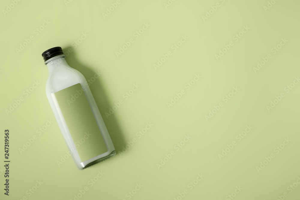 Glass bottle with white liquid (milk, cream, sauce) isolated on colour background