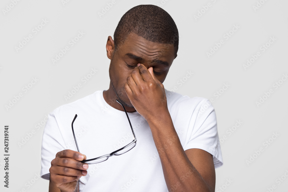 Tired african american man massaging nose bridge taking off glasses feeling  eye fatigue strain isolated on white grey studio background, young black  guy having headache dry irritable vision problem Stock Photo