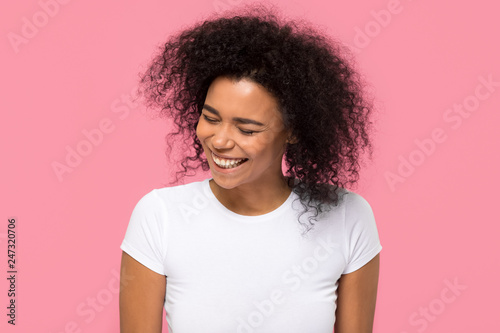Happy young african american mixed race girl laughing at funny joke isolated on pink blank studio background, cheerful millennial black woman having fun enjoy sincere positive emotions and laughter