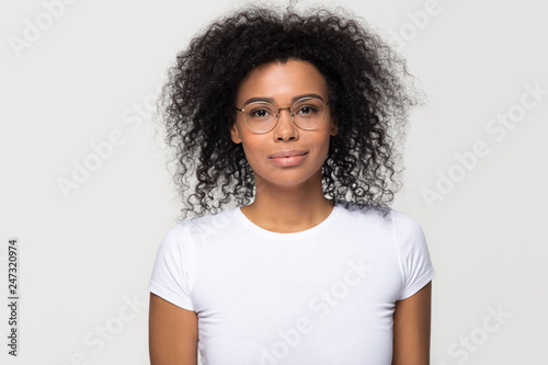 Confident smart attractive young african woman with afro hair wearing glasses looking at camera, millennial black lady isolated on blank grey white studio background, optics concept, portrait