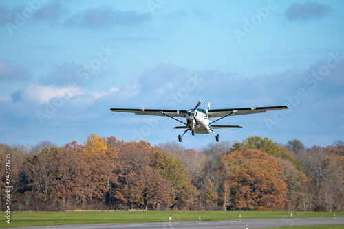 Single prop airplane taking off from the runway in autumn sunlight