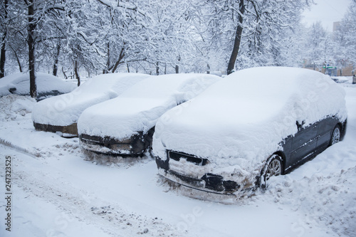 Three cars are covered with snow