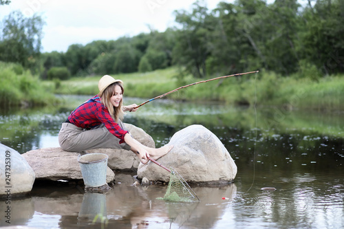 Girl by the river with a fishing rod