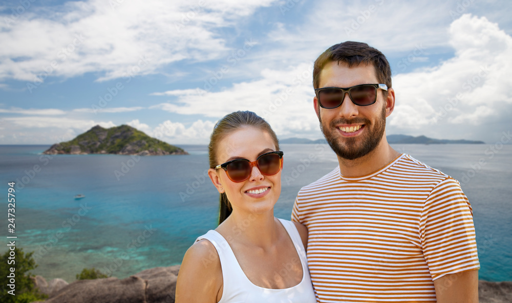 travel, tourism and people concept - happy couple in sunglasses outdoors over tropical beach on seychelles island background