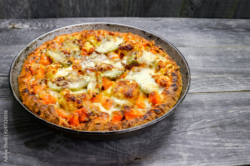 Pie with vegetables and cheese in the pan on a vintage grey wood rustic background
