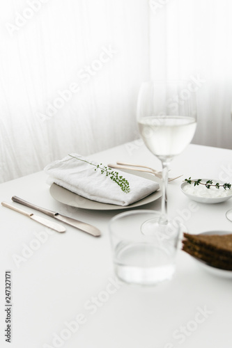 A dinner table with bread and cream cheese for starter, white wine and water to drink.