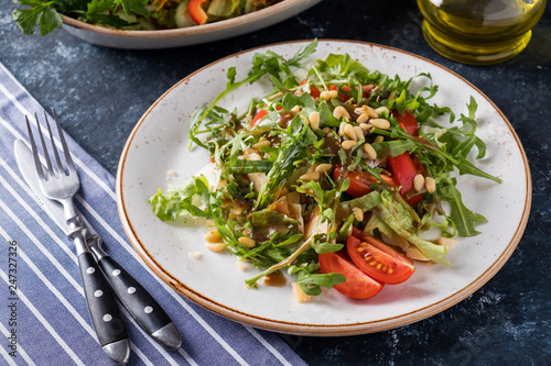 Tasty  salad with  arugula, cherry tomatoes and pine nuts in  a plate. Dieting