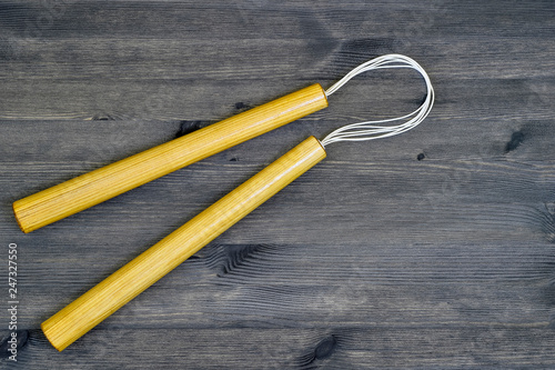 Nunchucks on vintage wooden background. The concept of invitation to training.