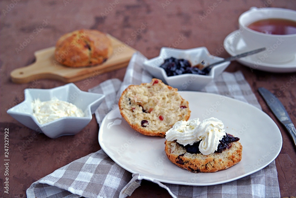 Traditional English scones with dried cranberries on a white plate. Served with jam and whipped cream. Traditional English scones with dried cranberries on a white plate. Served with jam and whipped cream.