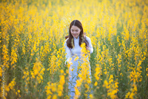 Beautiful women with traditional Vietnamese culture. Ao dai is a famous traditional costume, a walk in the forest, yellow soil nourishing plants. © somchai20162516