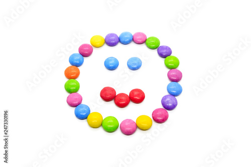 Smiley from multicolored chocolate glazed candies on white