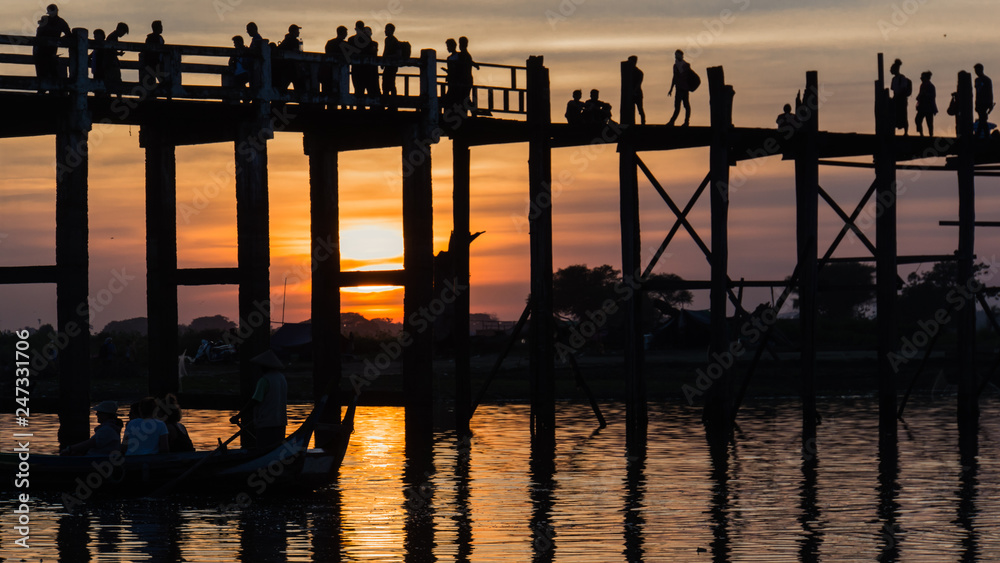 Iconic U-Bein Bridge, the longest teak foot bridge curves as it crosses the shallow Lake Taungthamanin, reflecting on the lake, Amarapura, Mandalay, Myanmar