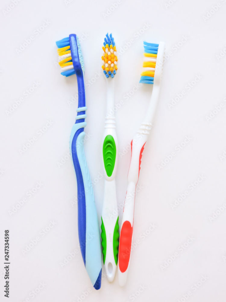 Flat lay composition with manual toothbrushes on white background.Toothbrush and toothpaste.op view, flat lay. Minimal concept, space for text.set of multicolored toothbrushes on white. Flat lay composition with manual toothbrushes on white background.Toothbrush and toothpaste.op view, flat lay. Minimal concept, space for text.set of multicolored toothbrushes on white.