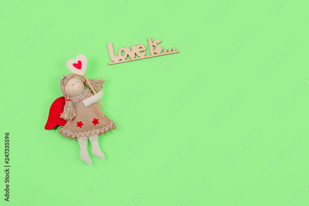 Valentines day pastel minimal creative background. Text Love is and toy angel, cupid, fairy on green background. Valentines day, Love, romance concept