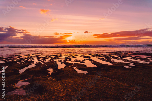 Ocean with waves and pastel sunset or sunrise in Bali.