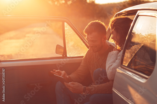 Beautiful couple on road trip, they are taking a break from driving and looking for direction on tablet. © Zoran Zeremski