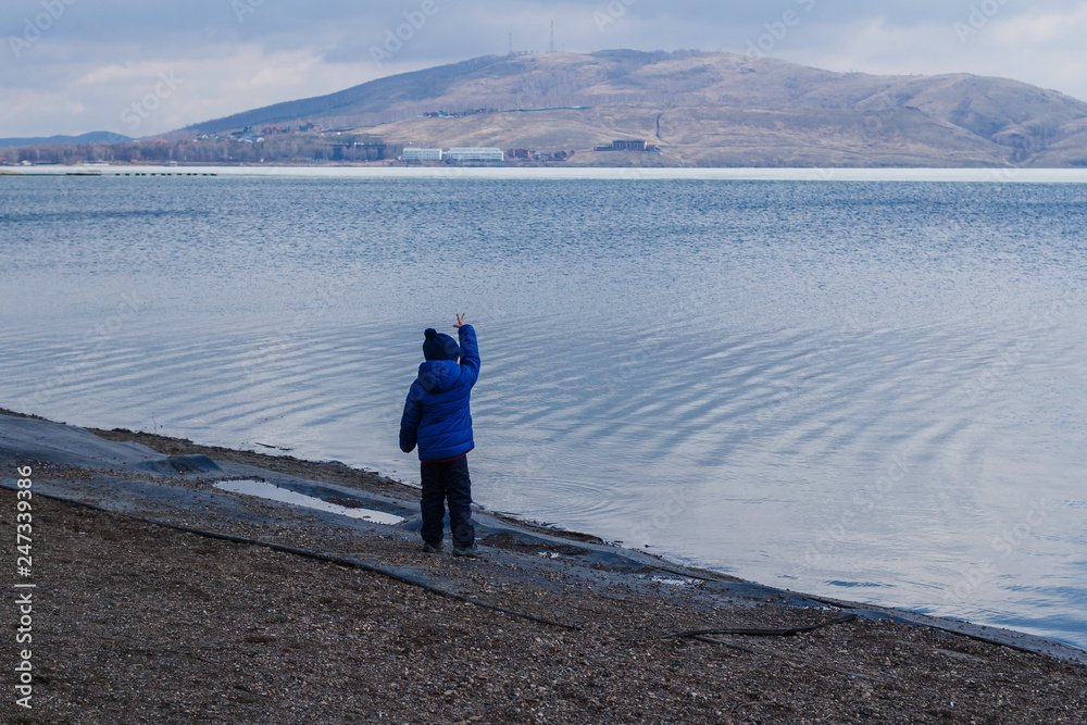 child stands next to the sea in spring child stands next to the sea in spring