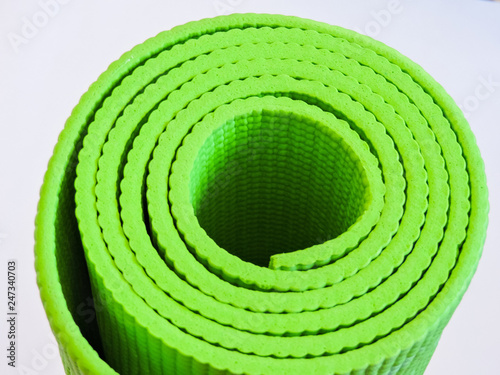 Woman rolling her Yoga mat after a workout - top view.Healthy life, keep fit concepts.Equipment for yoga. Top view green yoga mat sport isolated.Rolled up yoga mat isolated on white. Copyspace. 