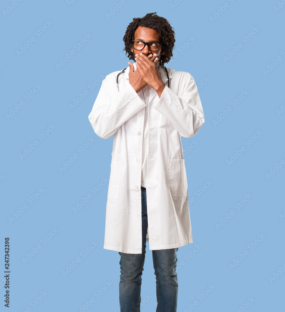 Handsome african american medical doctor covering mouth, symbol of silence and repression, trying not to say anything Handsome african american medical doctor covering mouth, symbol of silence and repression, trying not to say anything