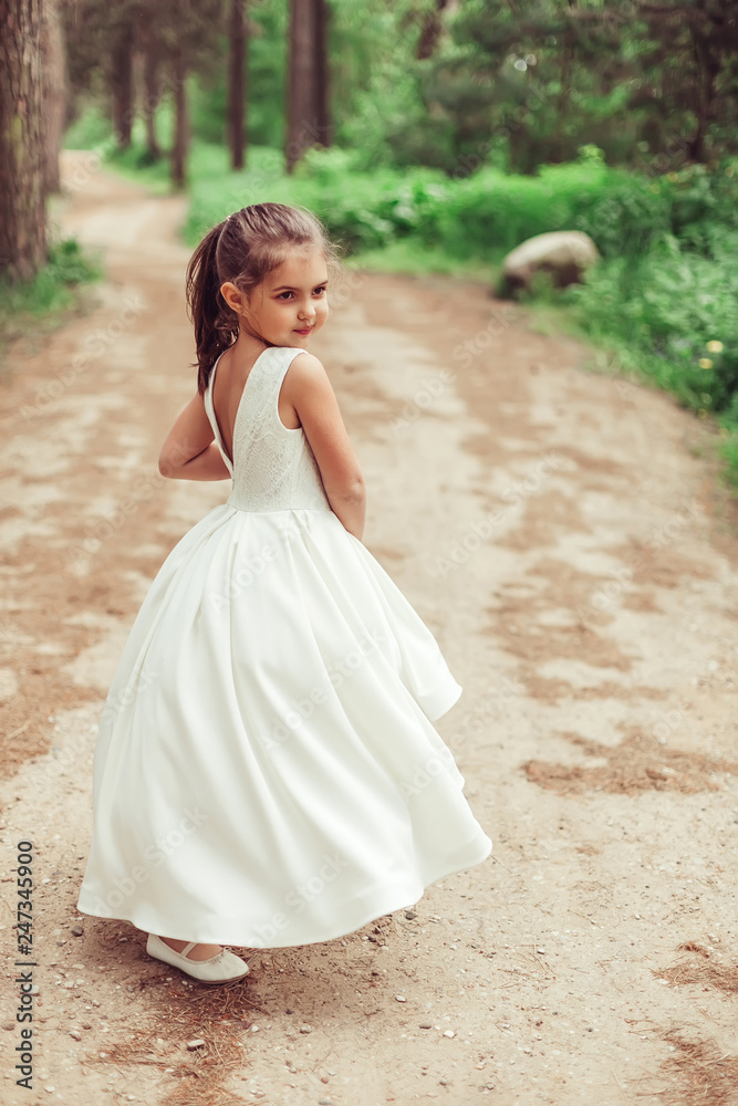 Outdoor portrait of cute brunette emotional girl dancing and having fun in elegant fashionable dress. Childhood, nature, fashion concept Outdoor portrait of cute brunette emotional girl dancing and having fun in elegant fashionable dress. Childhood, nature, fashion concept