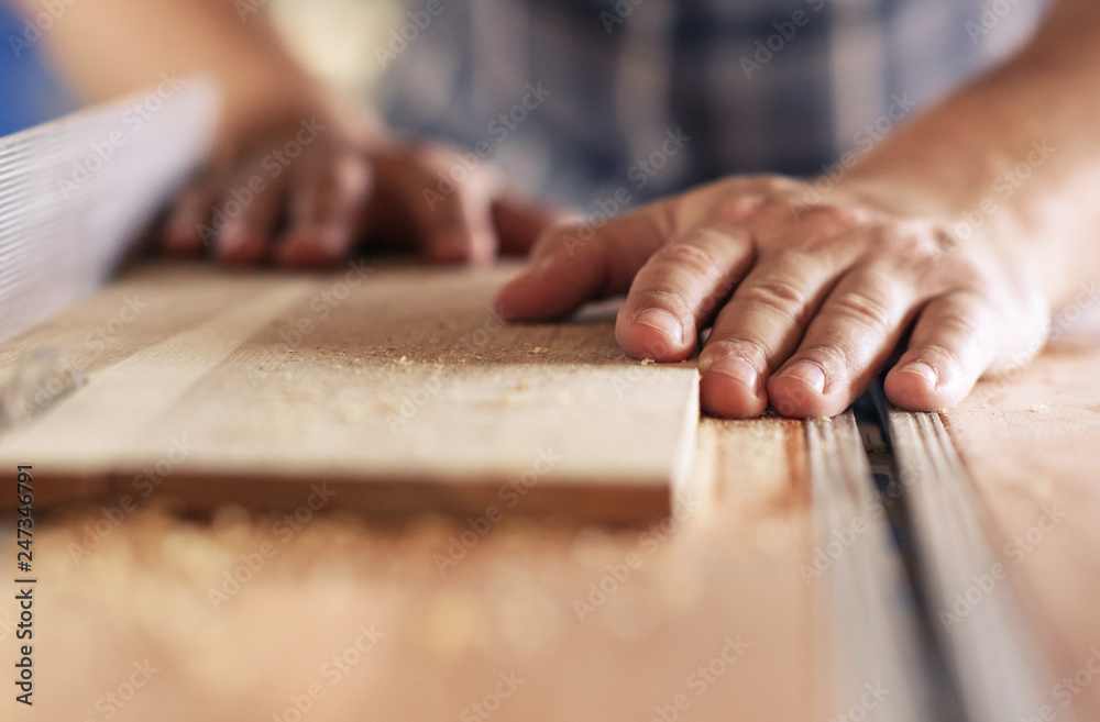 Craftsman sawing planks of wood in his carpentry workshop Craftsman sawing planks of wood in his carpentry workshop