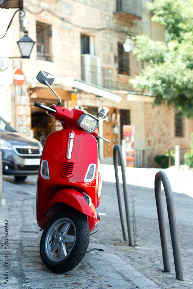 Red scooter parked in the street in the european sity