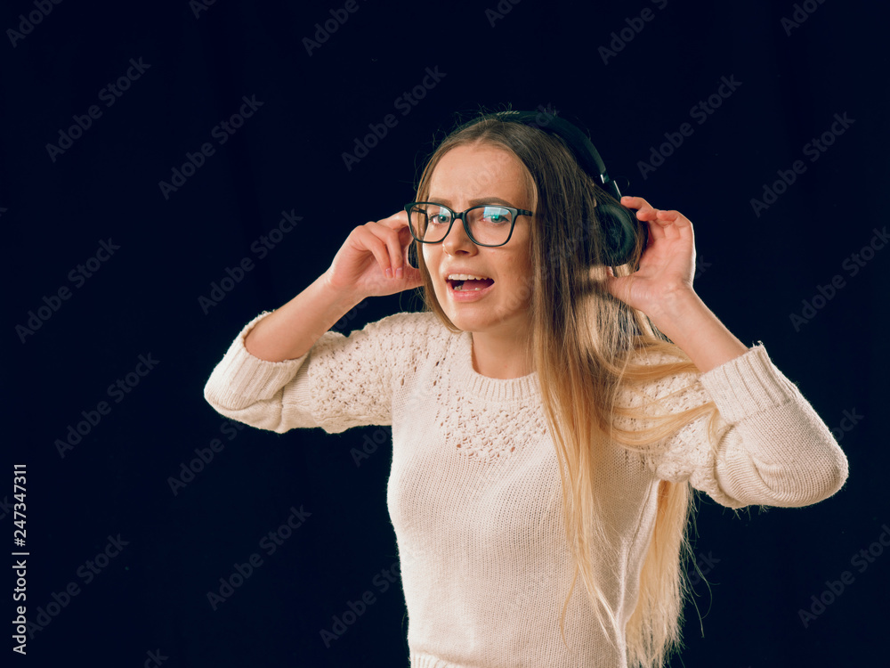 beautiful cheerful girl in headphones on black background.