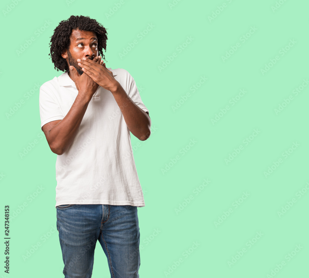 Handsome african american covering mouth, symbol of silence and repression, trying not to say anything Handsome african american covering mouth, symbol of silence and repression, trying not to say anything