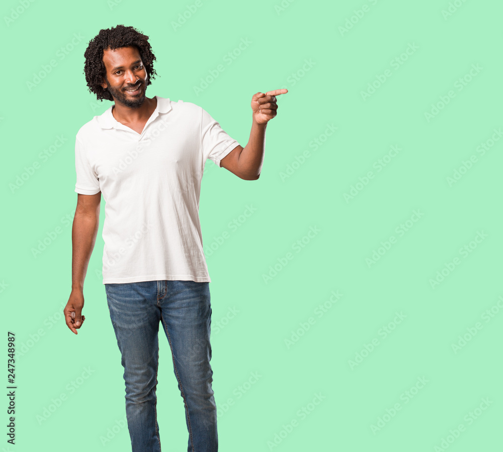 Handsome african american pointing to the side, smiling surprised presenting something, natural and casual Handsome african american pointing to the side, smiling surprised presenting something, natural and casual
